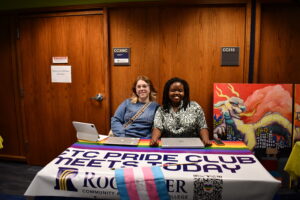 two students sit at a Pride Club table during an RCTC club fair