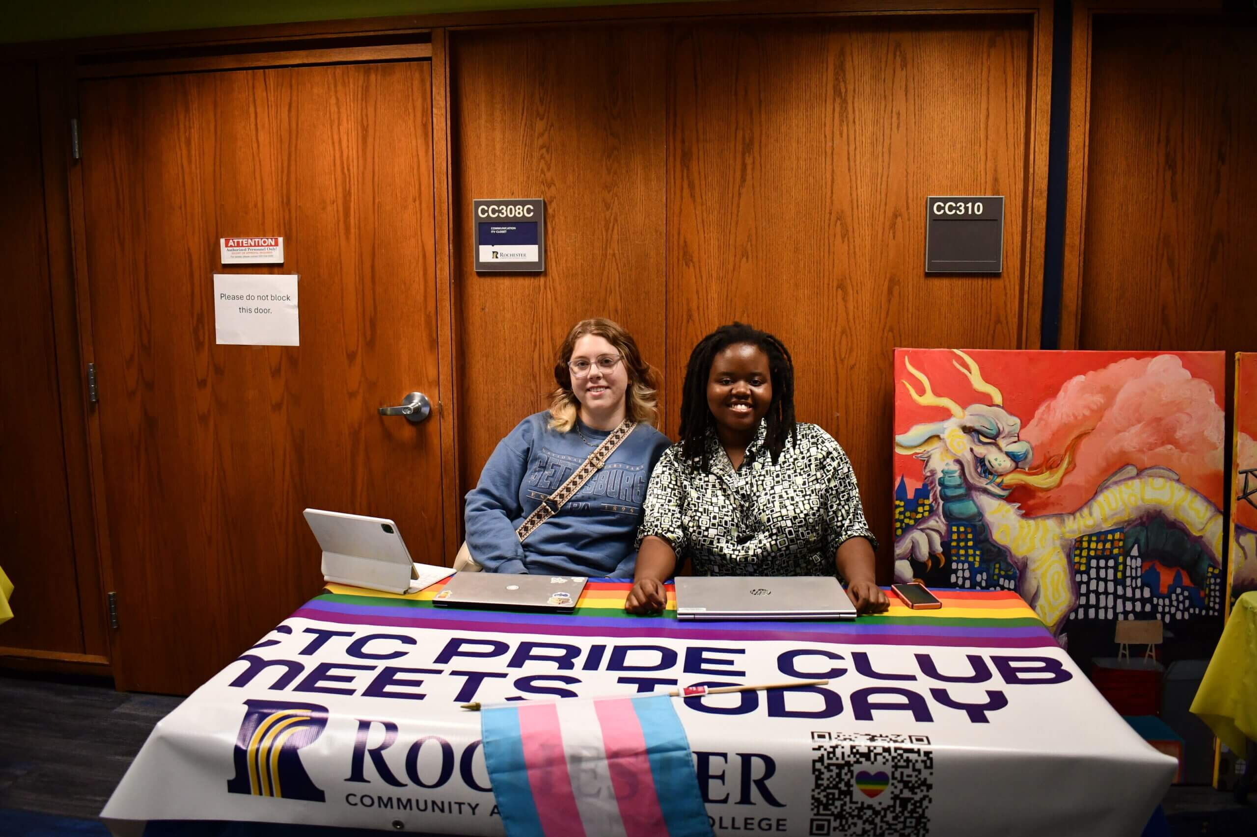 two students sit at a Pride Club table during an RCTC club fair