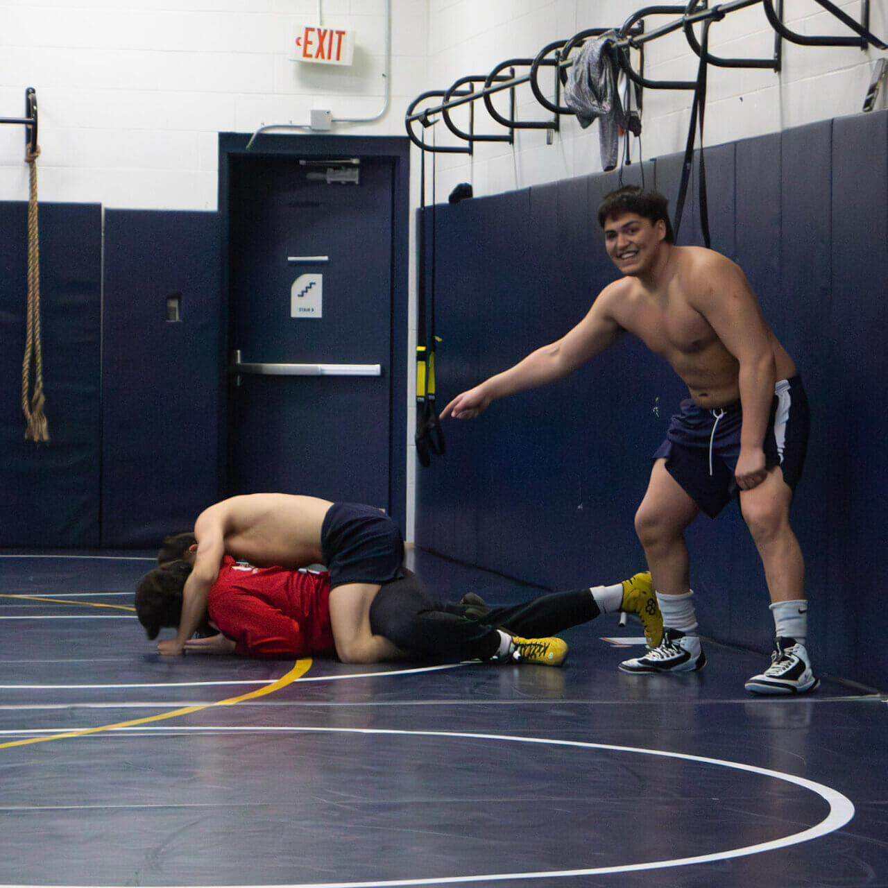 heavyweight All-American Cito Tuttle points at teammates Benito Diaz and Noah Ballweber play wrestling.