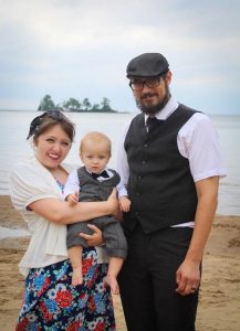 photo of woman holding son standing next to man on a beach